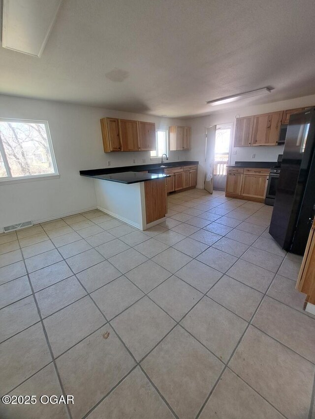 514 S Cole, Granby, MO 64844 - kitchen featuring light tile patterned flooring, visible vents, a peninsula, dark countertops, and appliances with stainless steel finishes