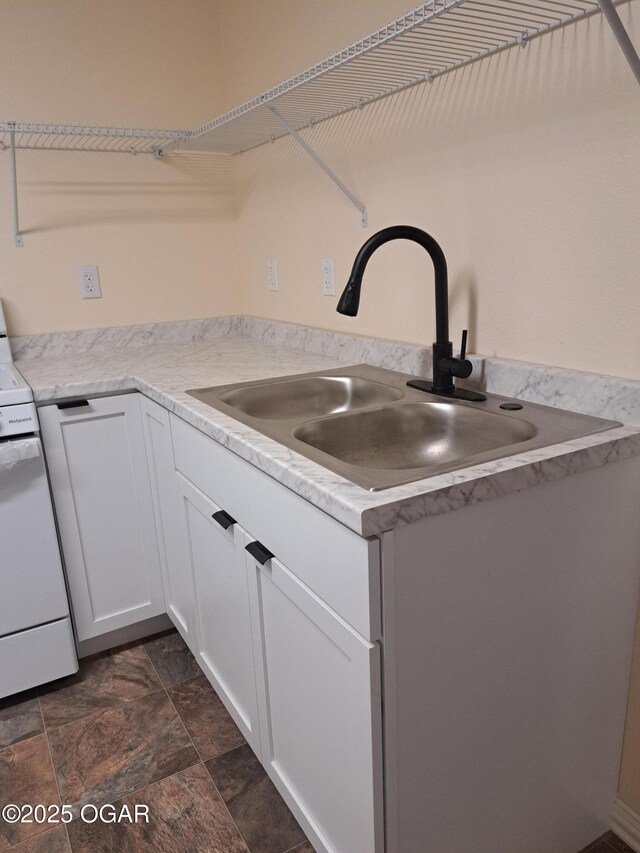 514 S Cole, Granby, MO 64844 - kitchen featuring range, light countertops, stone finish floor, white cabinetry, and a sink
