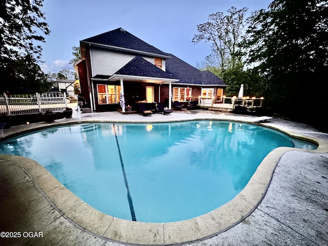 outdoor pool featuring a wooden deck, a patio area, outdoor lounge area, and fence