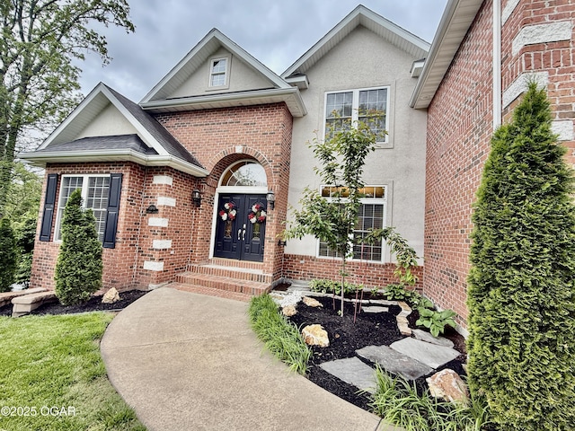 doorway to property with brick siding, stucco siding, and french doors