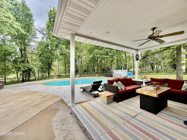 outdoor pool with outdoor lounge area, ceiling fan, a patio, and view of wooded area