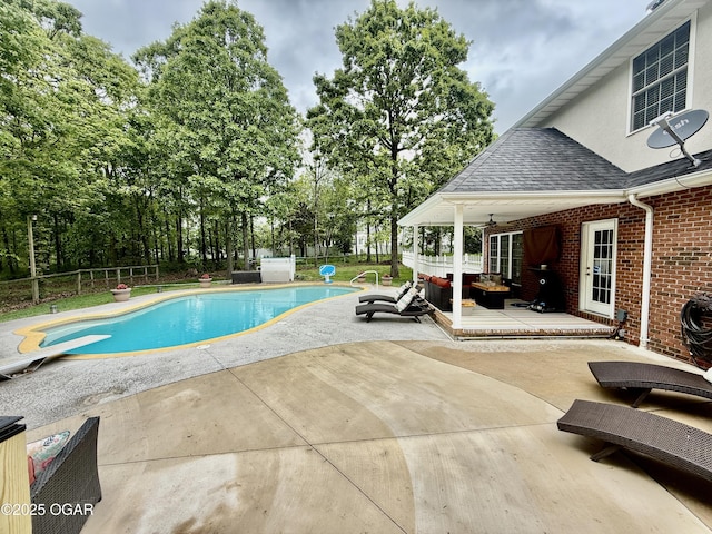 view of pool featuring a patio area, view of wooded area, a diving board, and fence