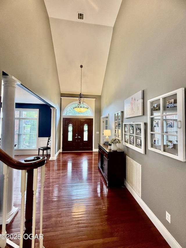 entrance foyer featuring high vaulted ceiling, dark wood-type flooring, baseboards, and decorative columns