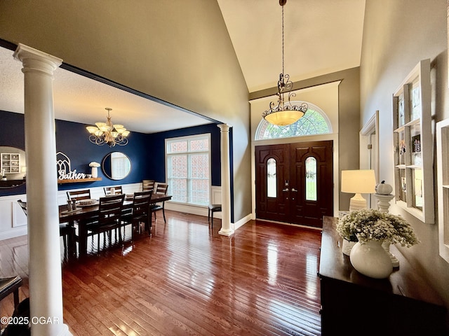 foyer with decorative columns, a chandelier, plenty of natural light, high vaulted ceiling, and hardwood / wood-style flooring
