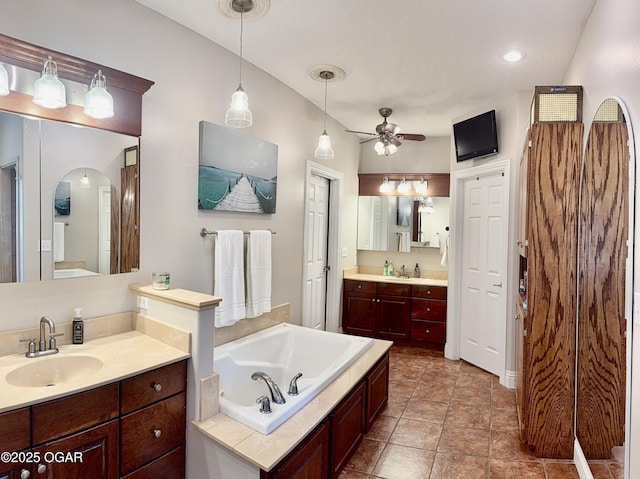 bathroom featuring a ceiling fan, a bath, and two vanities
