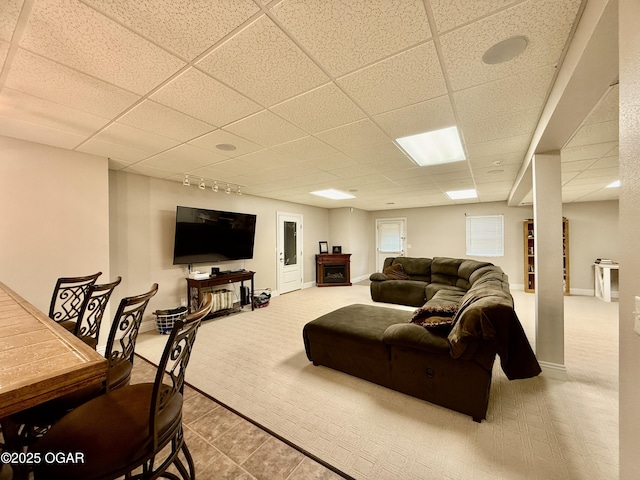 carpeted living room with a paneled ceiling, baseboards, track lighting, and tile patterned flooring