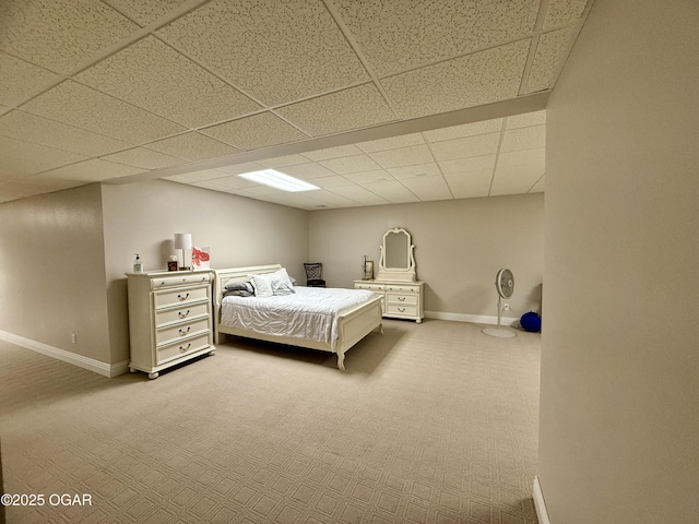 carpeted bedroom featuring baseboards and a drop ceiling
