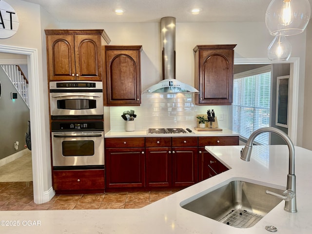1911 Sherry Lea Dr, Neosho, MO 64850 - kitchen featuring wall chimney range hood, a sink, stainless steel appliances, decorative backsplash, and pendant lighting