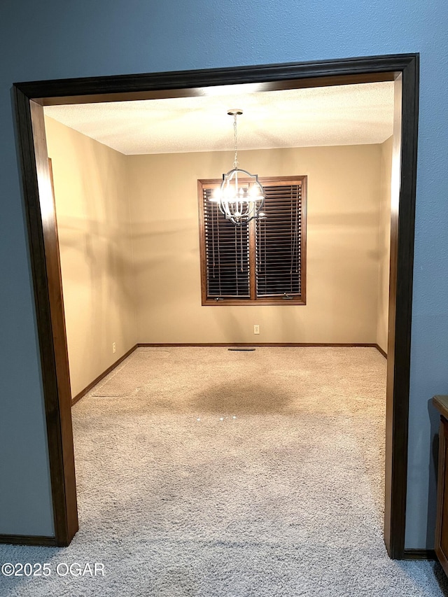 empty room with baseboards, carpet flooring, and a chandelier