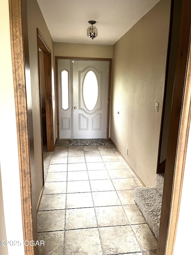 foyer entrance with a textured wall and a textured ceiling
