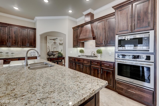 kitchen with light stone countertops, arched walkways, tasteful backsplash, a sink, and stainless steel appliances