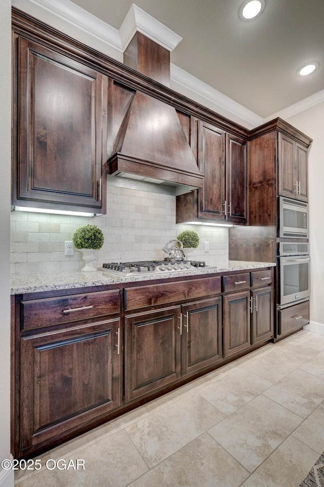 kitchen featuring crown molding, dark brown cabinets, appliances with stainless steel finishes, and tasteful backsplash