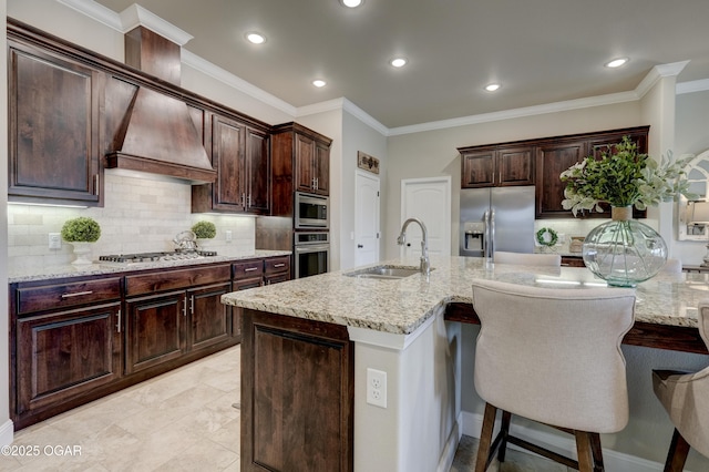 kitchen with a breakfast bar area, backsplash, appliances with stainless steel finishes, a sink, and recessed lighting
