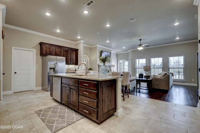 kitchen with a sink, arched walkways, a ceiling fan, baseboards, and stainless steel appliances