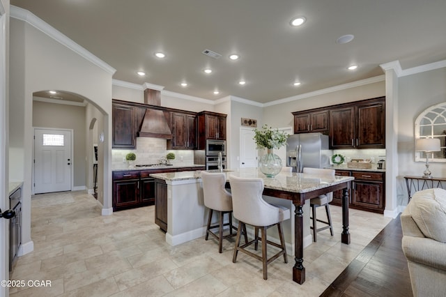 kitchen with stainless steel appliances, arched walkways, custom exhaust hood, and tasteful backsplash