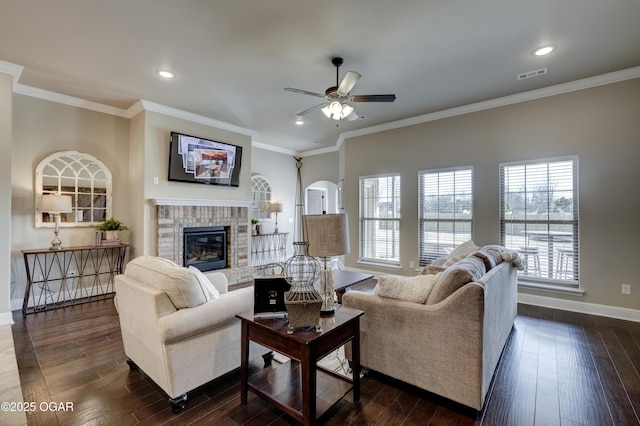 living area with visible vents, a fireplace, baseboards, dark wood-type flooring, and a ceiling fan