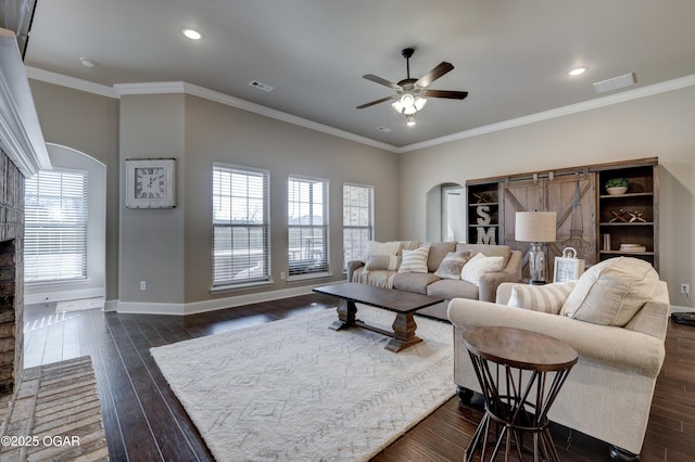 living area with arched walkways, ceiling fan, visible vents, and baseboards