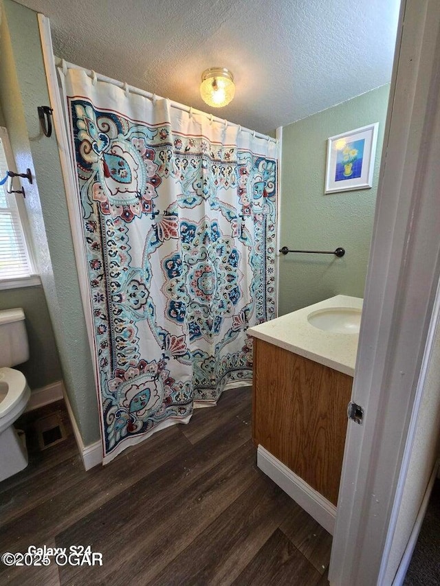 full bathroom with vanity, toilet, baseboards, a textured ceiling, and wood finished floors