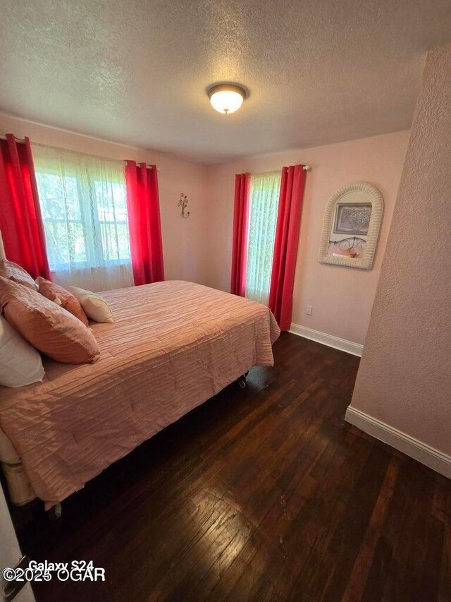 bedroom featuring hardwood / wood-style floors, baseboards, and a textured ceiling