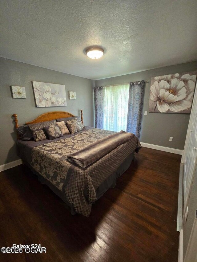 bedroom with a textured ceiling, baseboards, and wood finished floors