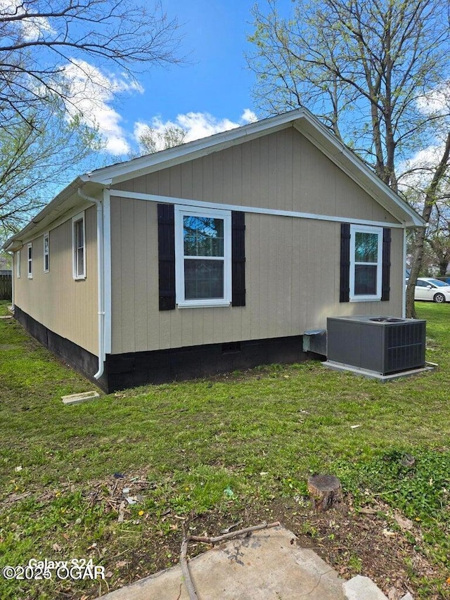 view of side of property featuring central AC unit and a lawn