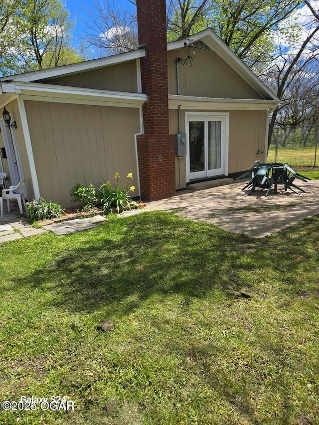rear view of house featuring a lawn and a patio