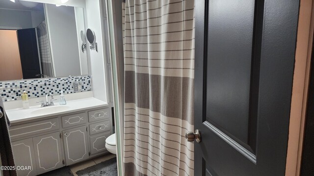 full bath with toilet, curtained shower, vanity, tasteful backsplash, and tile patterned flooring