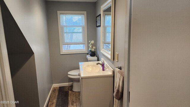 bathroom featuring baseboards, toilet, vanity, and wood finished floors