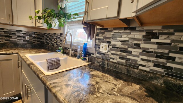 kitchen featuring white cabinetry, decorative backsplash, and a sink