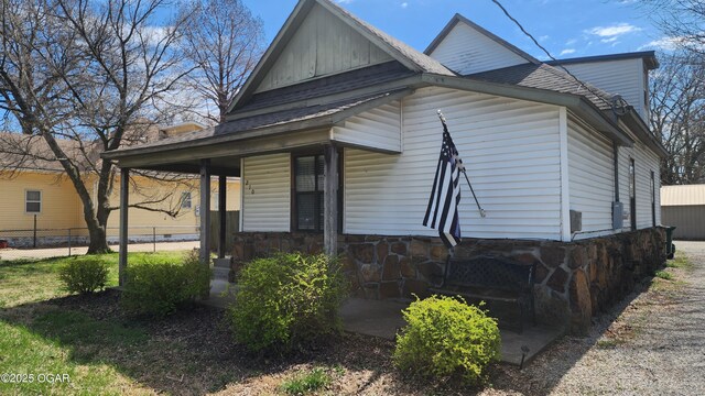 view of home's exterior with a shingled roof and fence