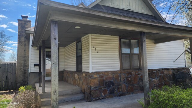 view of front of house featuring a chimney, fence, and a porch