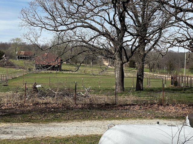 view of yard with fence and a rural view