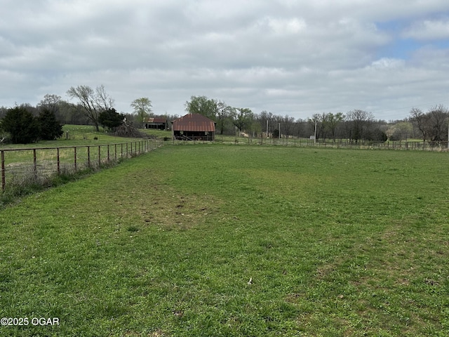 view of yard featuring an outdoor structure, fence, and a rural view