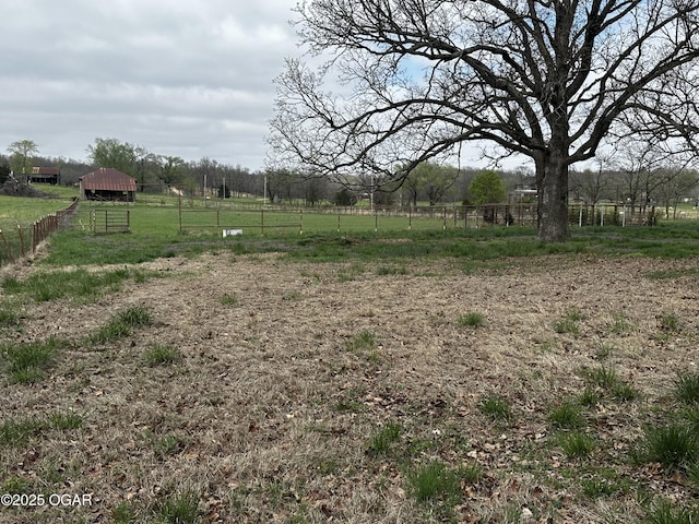 view of yard featuring an outdoor structure, an outbuilding, fence, and a rural view