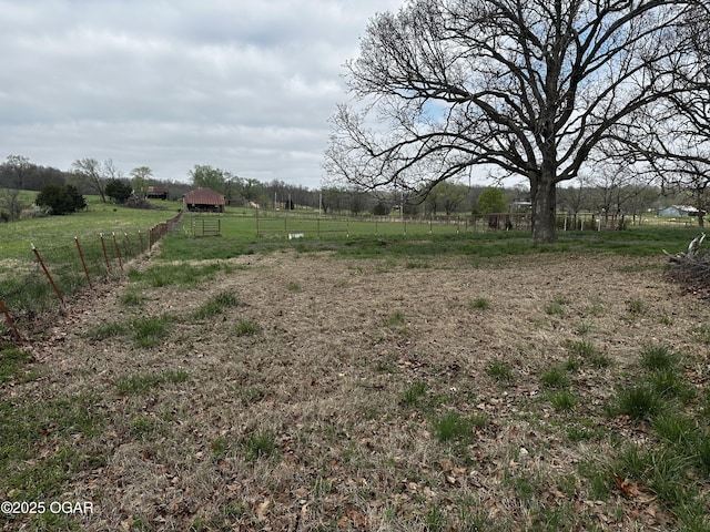 view of yard with an outdoor structure, fence, and a rural view