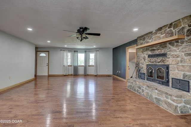 24600 State Highway 96, Webb City, MO 64870 - unfurnished living room featuring a fireplace, a textured ceiling, visible vents, ceiling fan, and wood finished floors
