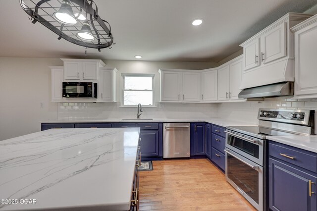 24600 State Highway 96, Webb City, MO 64870 - kitchen featuring white cabinetry, blue cabinetry, under cabinet range hood, appliances with stainless steel finishes, and a sink