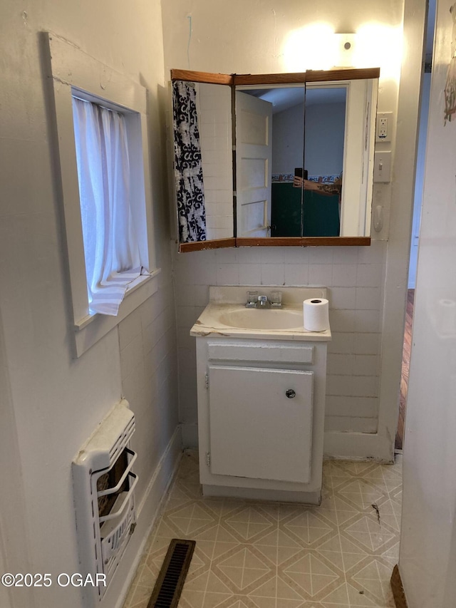 1320 W 4th St, Joplin, MO 64801 - bathroom featuring tile walls, heating unit, visible vents, and vanity