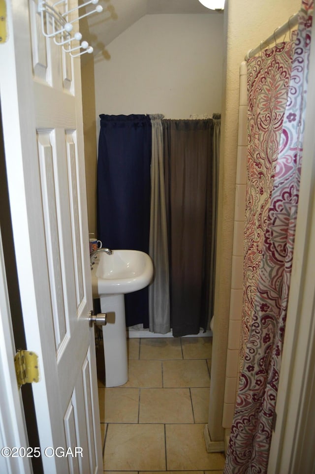 full bathroom featuring an inviting chandelier, tile patterned flooring, a sink, and lofted ceiling
