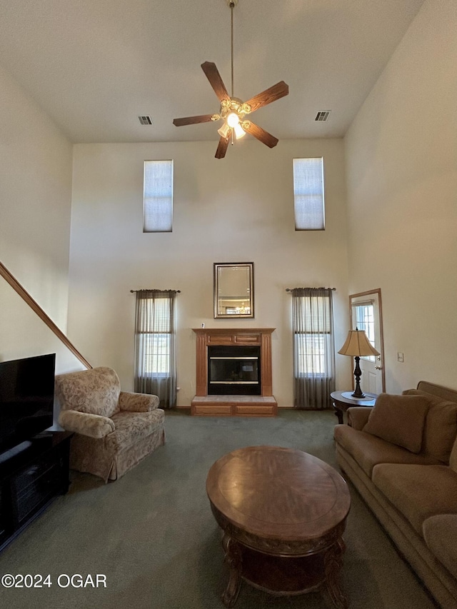 carpeted living area with visible vents, a glass covered fireplace, a healthy amount of sunlight, and ceiling fan