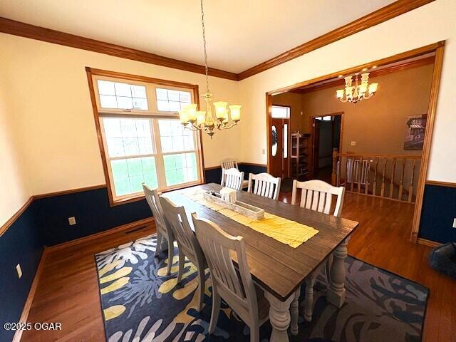 dining room with a chandelier, baseboards, crown molding, and wood finished floors