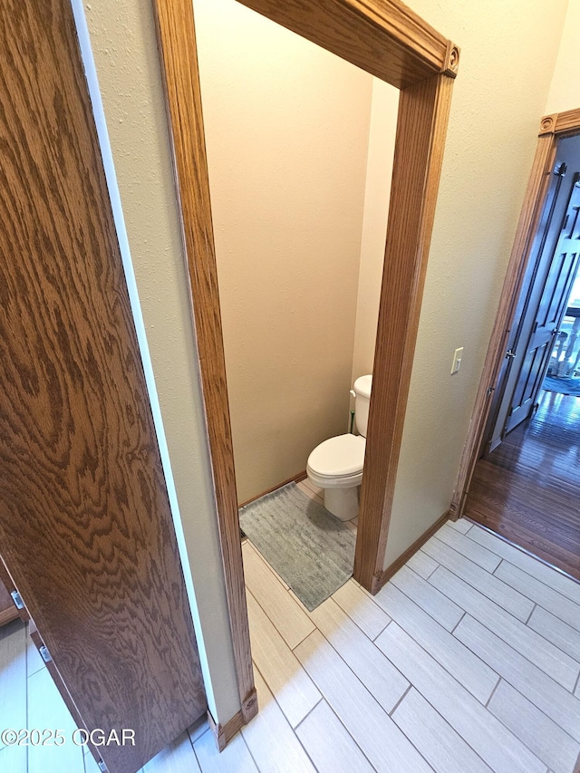 bathroom with baseboards, wood tiled floor, and toilet