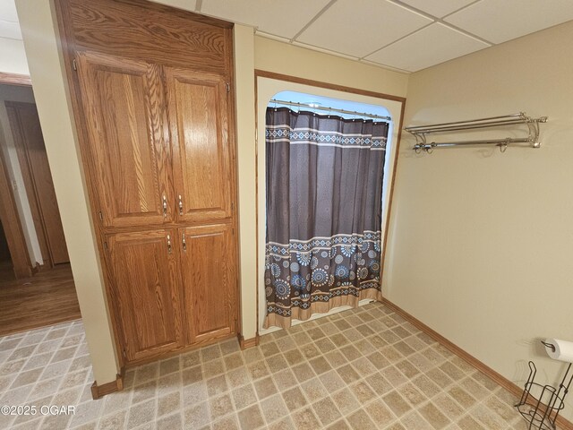 full bathroom featuring curtained shower, baseboards, and a drop ceiling