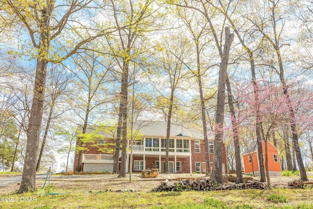 back of property featuring a sunroom, a wooden deck, and brick siding