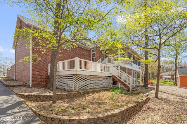 rear view of property featuring brick siding, a deck, and stairs
