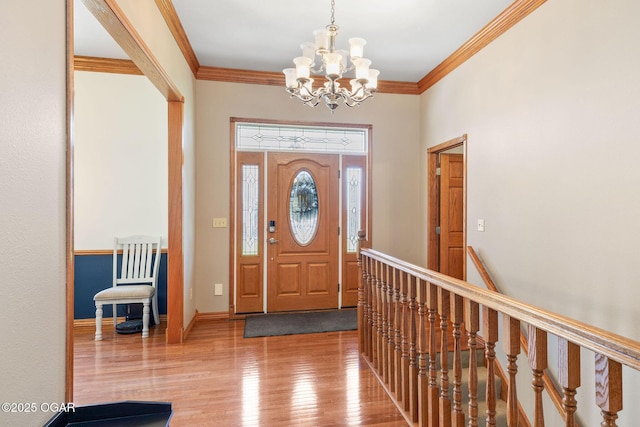 entryway with baseboards, an inviting chandelier, ornamental molding, and wood finished floors