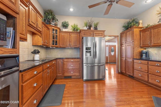 kitchen featuring brown cabinets, light wood finished floors, wall oven, and stainless steel fridge