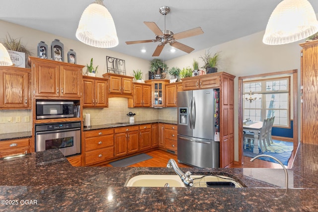 kitchen featuring brown cabinetry, appliances with stainless steel finishes, decorative backsplash, and a sink