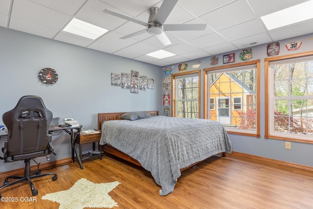 bedroom featuring visible vents, baseboards, ceiling fan, a paneled ceiling, and light wood-style floors