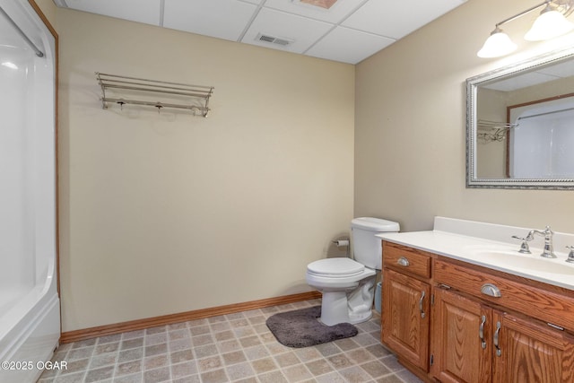 full bath with vanity, baseboards, a drop ceiling, and visible vents